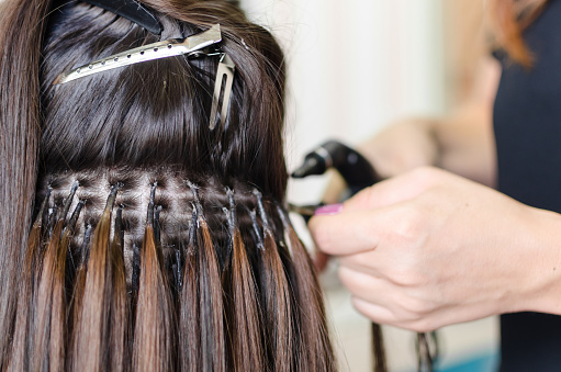A licensed cosmetologist must specifically place extensions